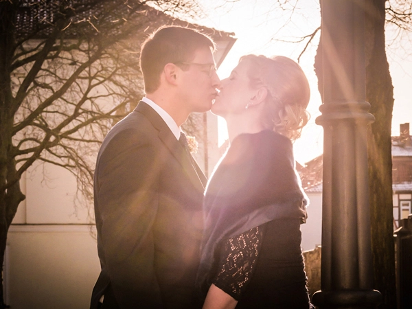 Brautpaar in Gegenlichtaufnahme bei einem liebevollen Kuss Nahaufnahme eines Brautpaares, das sich innig küsst, von der Seite im warmen Gegenlicht fotografiert. Die Lichtstrahlen erzeugen einen goldenen Schein um die Köpfe. Ein romantischer Moment, festgehalten von Hochzeitsfotograf Michael Schalansky.